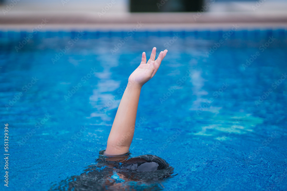 child in danger drowning in the pool,  kid girl cannot swim to deep water and raise two hand for help on swimming pool.