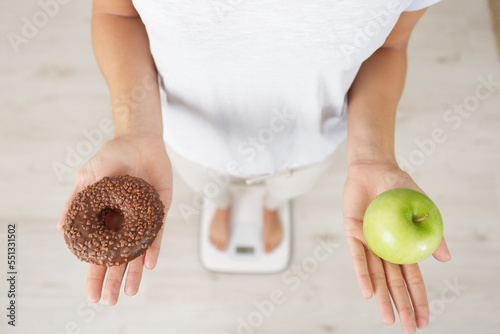 choosing between apple and donut - concept of healty lifestyle photo