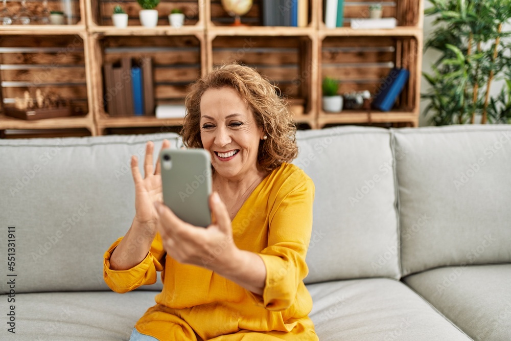 Middle age caucasian woman having video call using smartphone sitting on the sofa at home. Middle age caucasian woman having video call using smartphone sitting on the sofa at home.