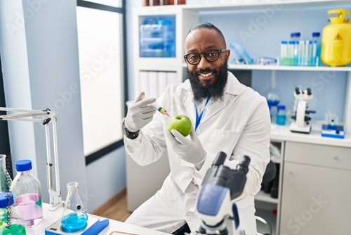 African american man working at scientist laboratory with apple smiling with a happy and cool smile on face. showing teeth.