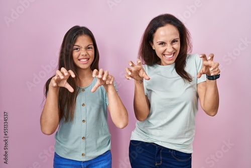 Photography Young mother and daughter standing over pink background smiling funny doing claw