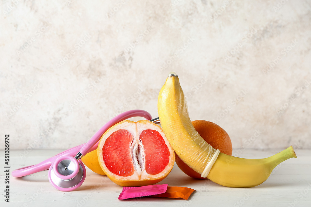 Fruits with stethoscope and condoms on beige background. Sex concept - obrazy, fototapety, plakaty 