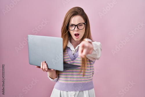 Young caucasian woman working using computer laptop pointing displeased and frustrated to the camera, angry and furious with you