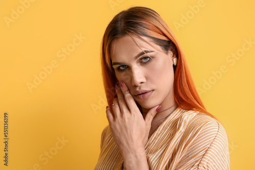 Young transgender woman with beautiful manicure on yellow background