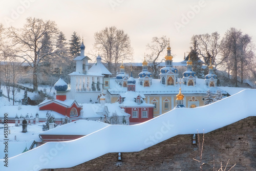 Fortress wall and churches of Holy Dormition Pskovo Pechersky Male Monastery in the town of Pechora, Pskov Region, Russia, on a winter snow sunny day photo