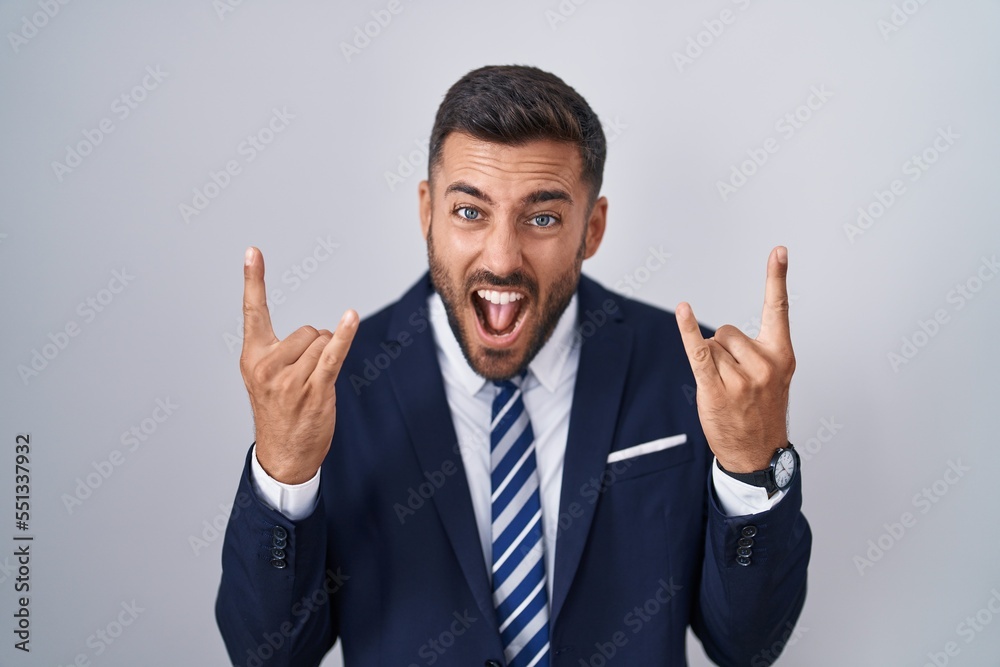 Handsome hispanic man wearing suit and tie shouting with crazy expression doing rock symbol with hands up. music star. heavy music concept. Handsome hispanic man wearing suit and tie shouting with crazy expression doing rock symbol with hands up. music star. heavy music concept.