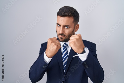 Handsome hispanic man wearing suit and tie ready to fight with fist defense gesture, angry and upset face, afraid of problem © Krakenimages.com
