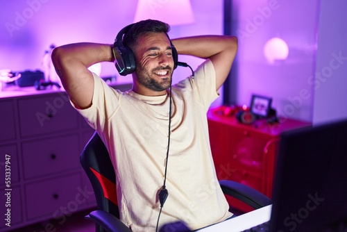 Young hispanic man streamer smiling confident relaxed with hands on head at gaming room photo