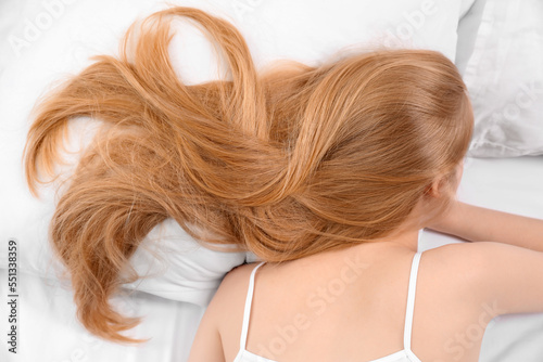 Blonde woman with long hair lying on soft bed