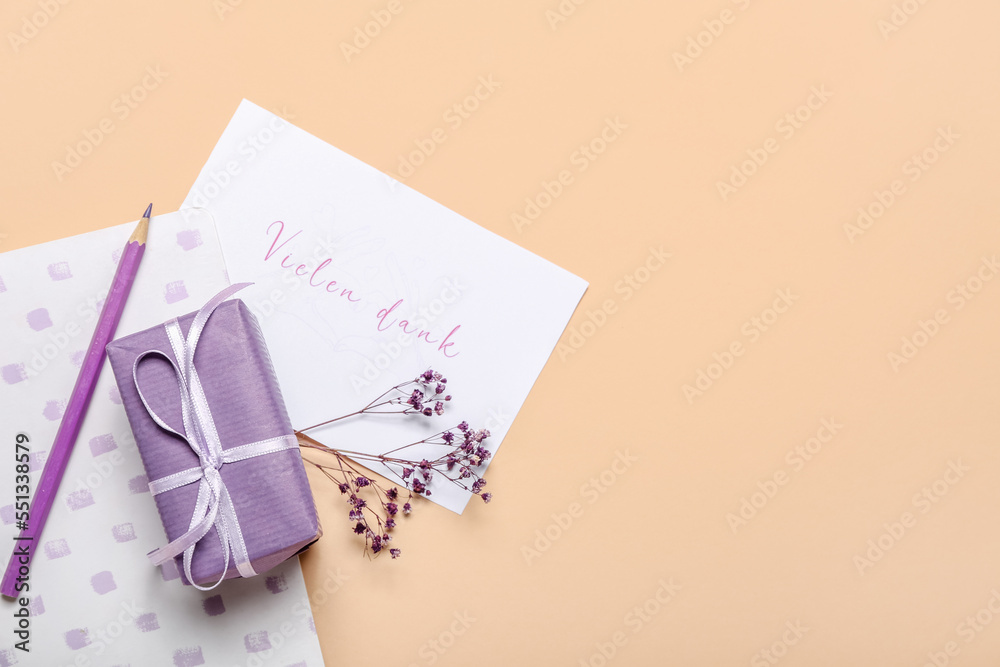 Naklejka premium Composition with card, gift box, notebook and pencil on color background