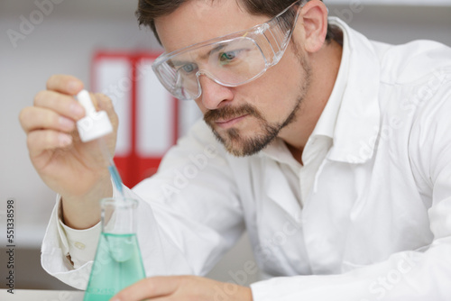 man is looking into the glass of microscope doing reseach photo