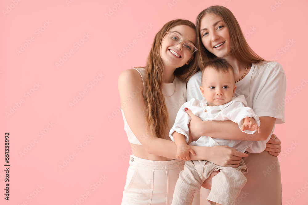 Happy lesbian couple with their little baby on pink background Happy lesbian couple with their little baby on pink background