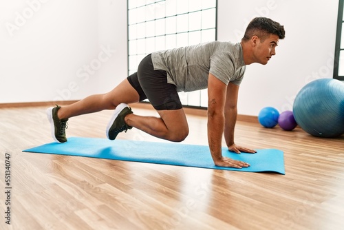 Young hispanic man training abs exercise at sport center