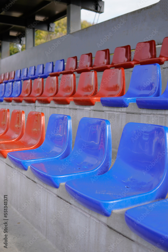 Fototapeta premium Tier of empty blue and red seats on a soccer field. Row of seats in the barça colours