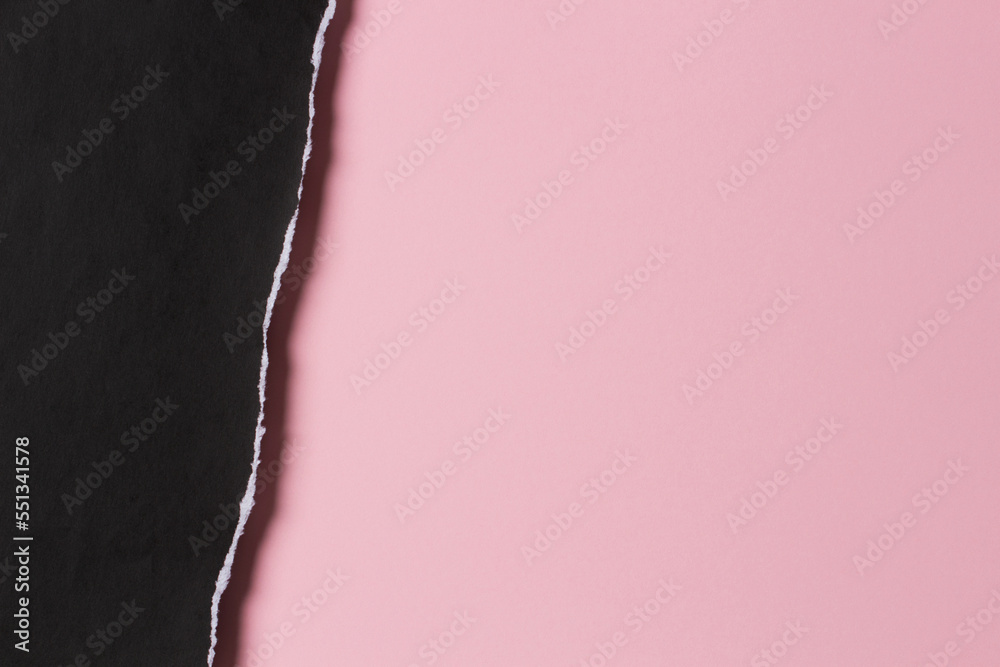 Black grunge ripped torn paper piece with ragged edge on pastel pink color paper background. Top view, copy space Black grunge ripped torn paper piece with ragged edge on pastel pink color paper background. Top view, copy space
