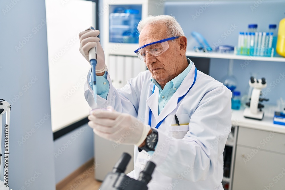 Senior man wearing scientist uniform using pipette working at laboratory Senior man wearing scientist uniform using pipette working at laboratory