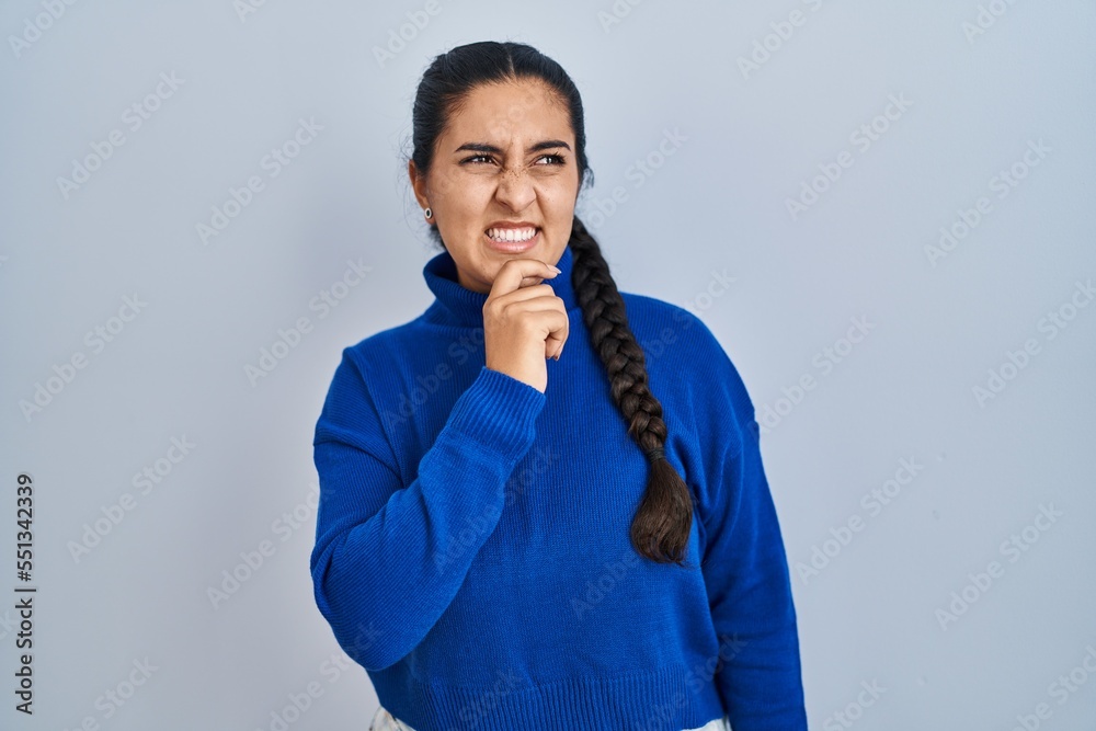 Young hispanic woman standing over isolated background thinking worried about a question, concerned and nervous with hand on chin Young hispanic woman standing over isolated background thinking worried about a question, concerned and nervous with hand on chin