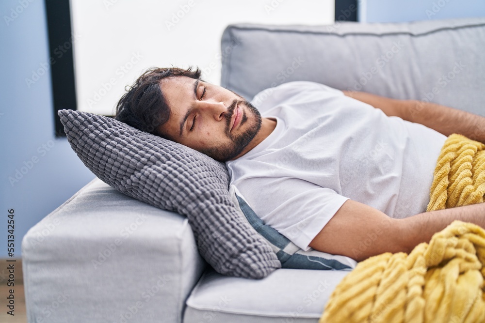 Fototapeta premium Young hispanic man lying on sofa sleeping at home