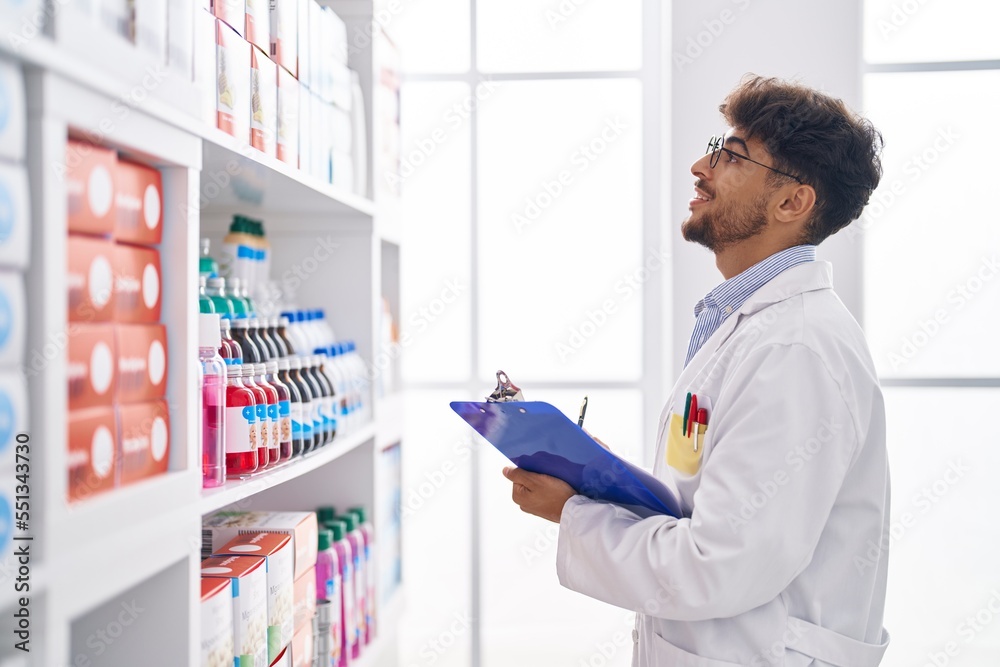 Young arab man pharmacist smiling confident writing on clipboard at pharmacy Young arab man pharmacist smiling confident writing on clipboard at pharmacy