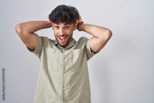Arab man with beard standing over white background posing funny and crazy with fingers on head as bunny ears, smiling cheerful