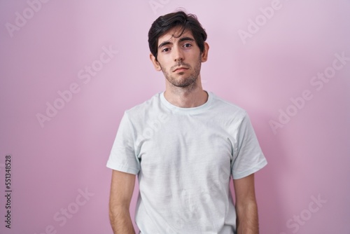 Young hispanic man standing over pink background depressed and worry for distress, crying angry and afraid. sad expression.