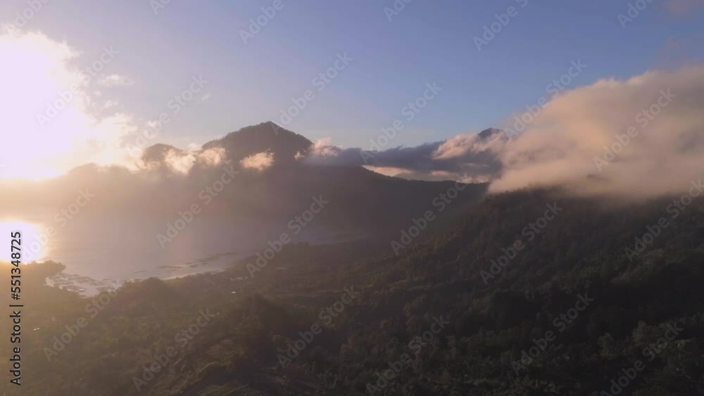 Flying in clouds with beautiful sunrise and view on mountain lake and a volcano. Aerial view, drone shot Flying in clouds with beautiful sunrise and view on mountain lake and a volcano. Aerial view, drone shot