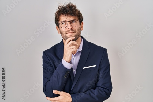 Hispanic business man wearing glasses with hand on chin thinking about question, pensive expression. smiling with thoughtful face. doubt concept. © Krakenimages.com