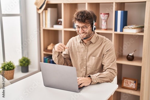 Hispanic young man wearing call center agent headset pointing finger to one self smiling happy and proud