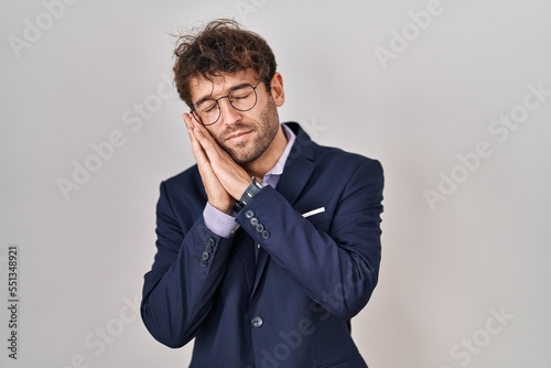 Hispanic business man wearing glasses sleeping tired dreaming and posing with hands together while smiling with closed eyes.