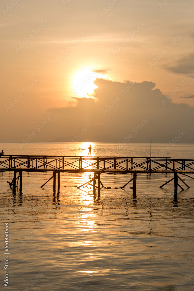 Silhouette of man fishing on jetty on mabul island at sunset in borneo