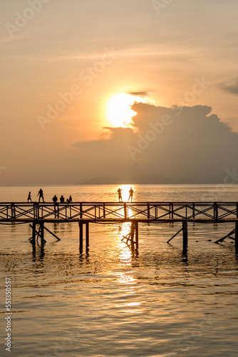 Silhouette of man fishing on jetty on mabul island at sunset in borneo photo