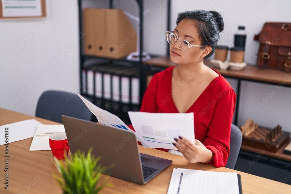 Young chinese woman business worker using laptop reading document at office Young chinese woman business worker using laptop reading document at office