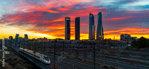Madrid. Four towers over the railways with high speed train. Colourful sky at sunset in a winter day.