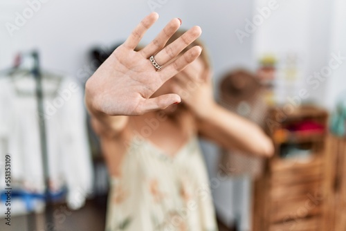 Young caucasian woman at retail shop covering eyes with hands and doing stop gesture with sad and fear expression. embarrassed and negative concept.