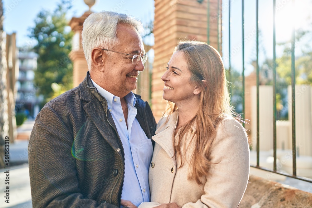 Middle age man and woman couple hugging each other standing at street Middle age man and woman couple hugging each other standing at street