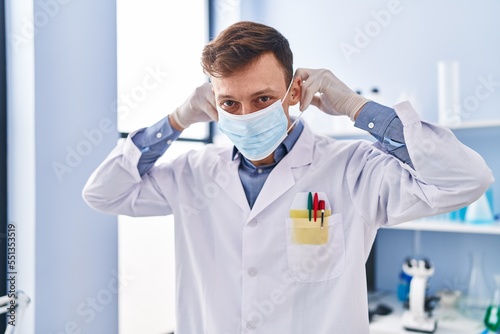 Young man scientist wearing medical mask standing at laboratory