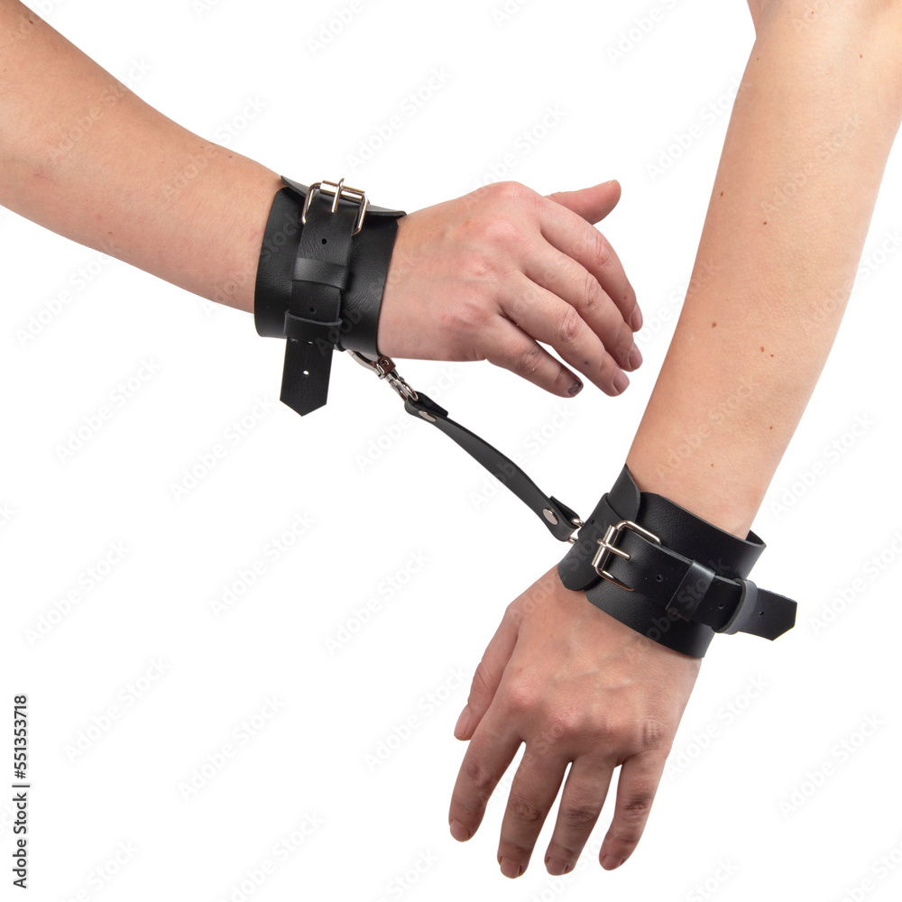 Toy black leather handcuffs on hand isolated on the white background