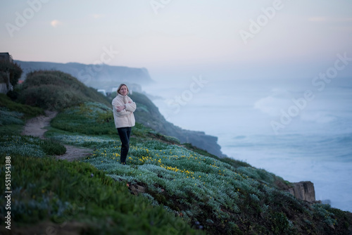 A woman meets the sunrise on the coast of the Atlantic Ocean. Sintra, Portugal.