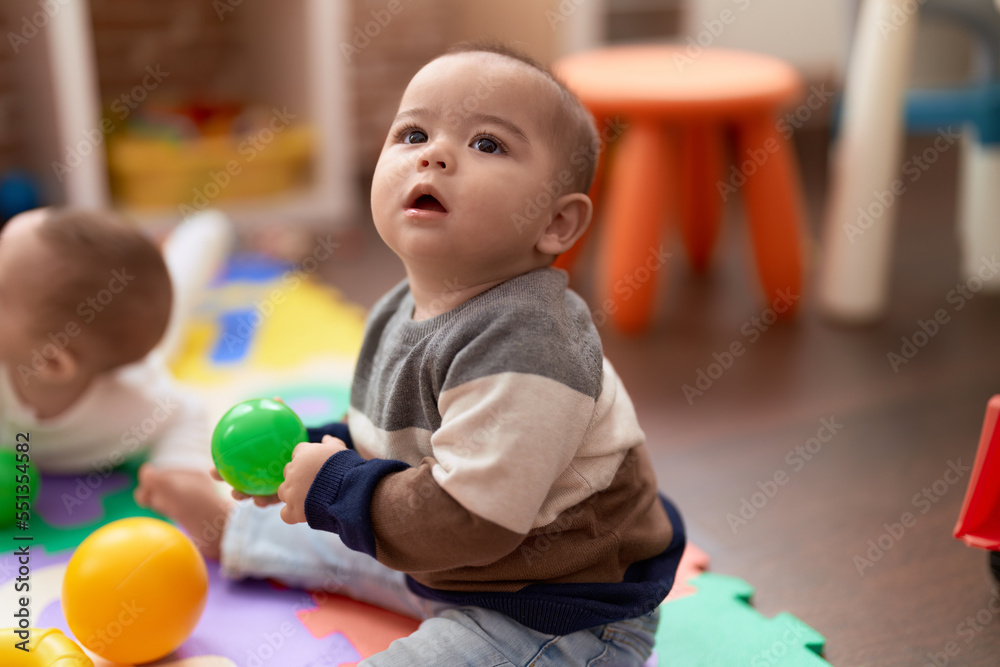 Adorable chinese toddler playing with ball sitting on floor at kindergarten Adorable chinese toddler playing with ball sitting on floor at kindergarten