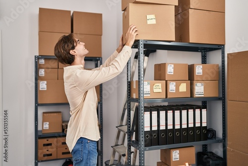 Fotografija Young caucasian man ecommerce business worker putting package on shelving at off