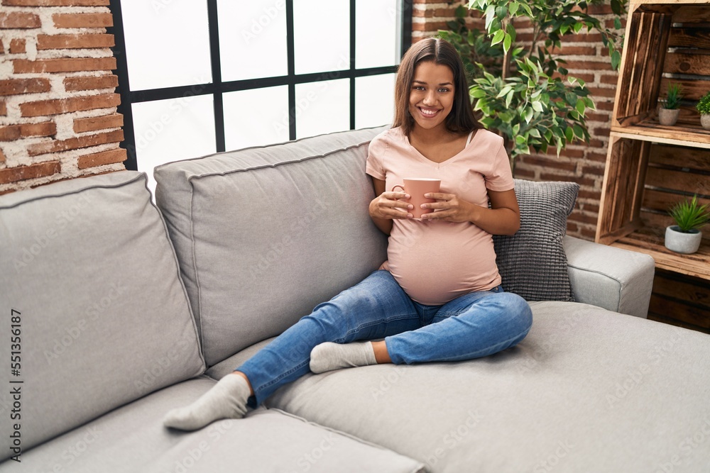 Young latin woman pregnant drinking coffee sitting on sofa at home Young latin woman pregnant drinking coffee sitting on sofa at home