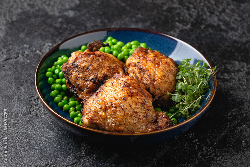 Baked Chicken thighs with green peas in blue plate