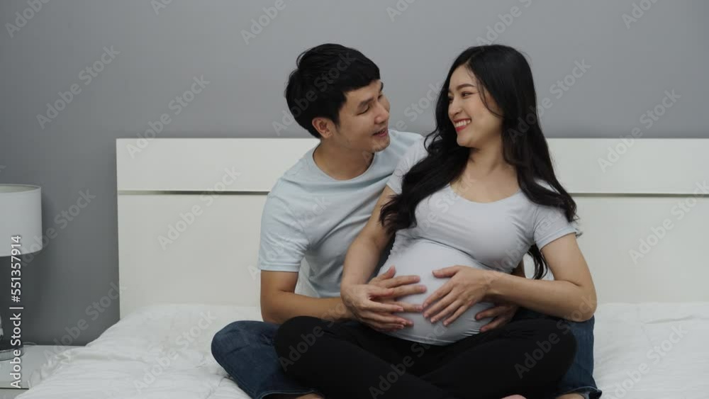 married couple is expecting baby. man embraces his pregnant wife on a bed married couple is expecting baby. man embraces his pregnant wife on a bed