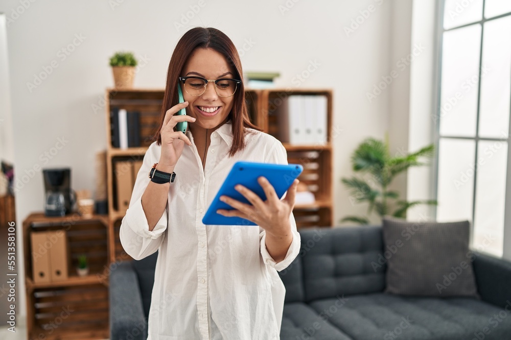 Young beautiful hispanic woman business worker talking on smartphone using touchpad at office Young beautiful hispanic woman business worker talking on smartphone using touchpad at office