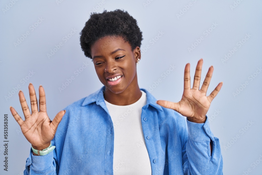 African american woman standing over blue background showing and pointing up with fingers number ten while smiling confident and happy.