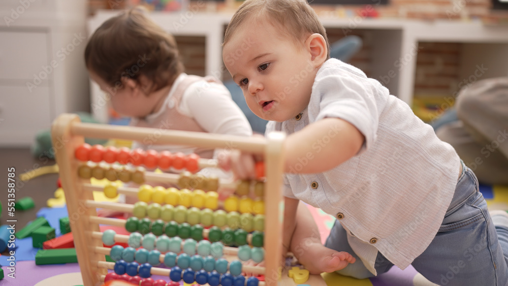 Two toddlers playing with abacus sitting on floor at kindergarten Two toddlers playing with abacus sitting on floor at kindergarten