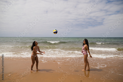 Two young and beautiful women playing boley on the shore of the beach. The women are enjoying the game and their day at the beach in paradise. Holidays and travels. photo