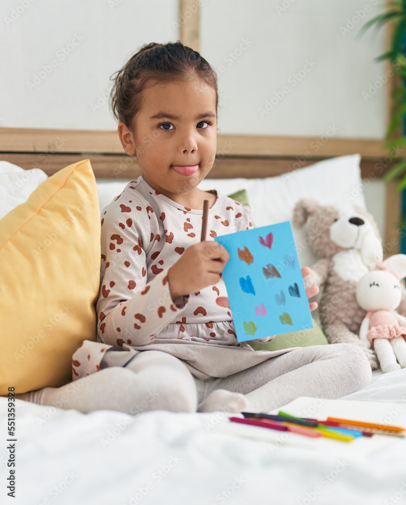 Adorable hispanic girl drawing on notebook sitting on bed at bedroom Adorable hispanic girl drawing on notebook sitting on bed at bedroom