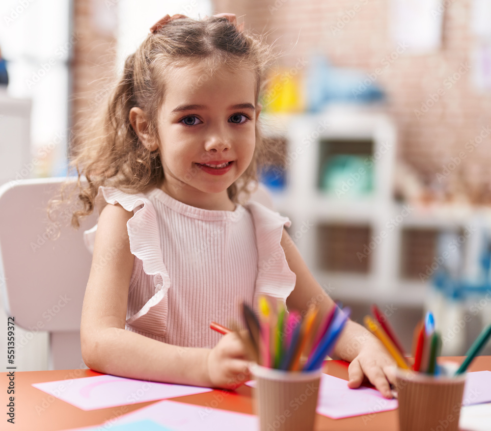 Adorable caucasian girl playing with construction blocks sitting on table at classroom Adorable caucasian girl playing with construction blocks sitting on table at classroom