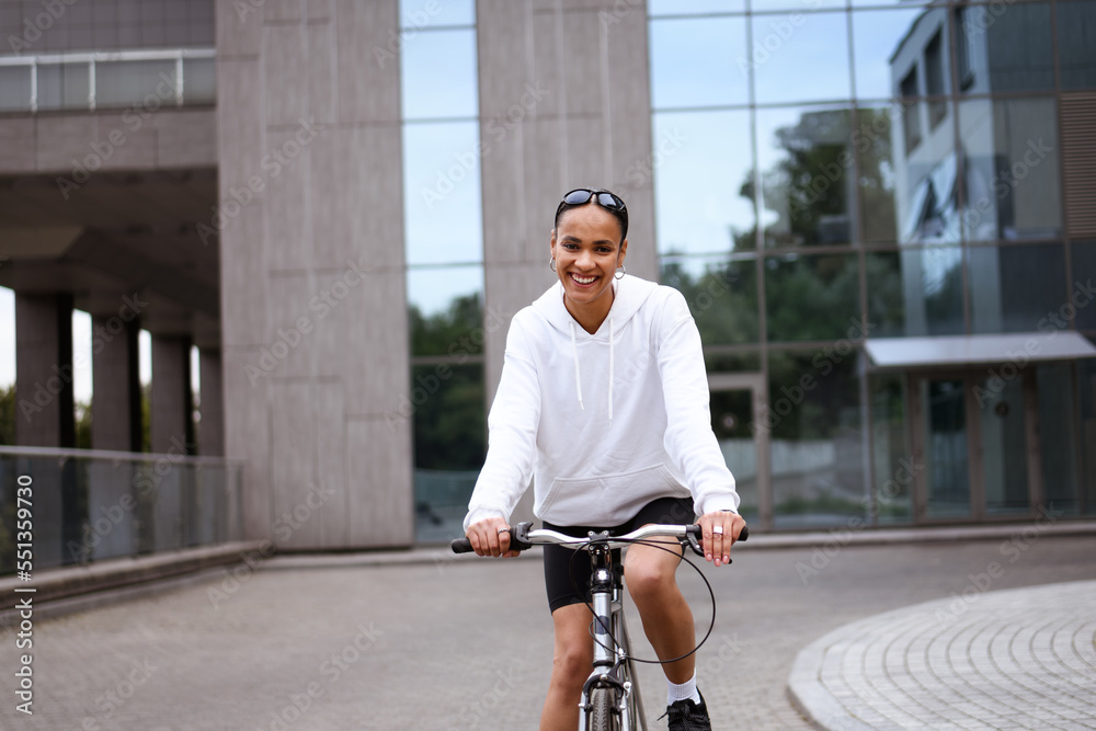 Obraz premium Pleased african american woman looking at camera while cycling outdoors 